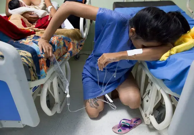 Venezuelan migrant Yulianis Rodriguez, hunches down in Maicao, Colombia's Hospital San Jose as she struggles to cope with the pain of labor without an epidural on May 5, 2019. She crossed into Colombia alone to give birth to her baby son who was born 'stateless' and is now among 24,000 children who were granted Colombian citizenship by the country's government. Image by Megan Janetsky. Colombia, 2019.