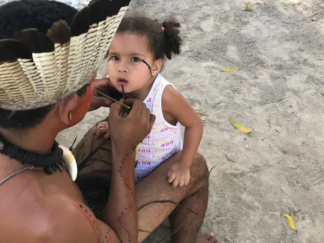 Mucunã (father) painting his daughter Micaela in preparation for a dance. Strong colors like black are reserved for times of battle and resistance among the Potiguaras of Catu. Image by Rafael Lima. Brazil, 2019.
