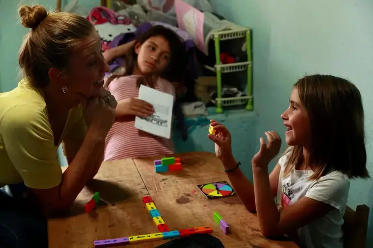 Inside Joy’s store, she, Maya and Catalina play an English-language game of W-I-N-G-O, kind of a cross between Scrabble and Bingo. Image by Erika Schultz. Mexico, 2019.