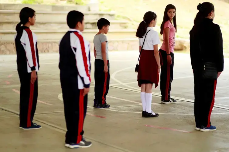 Maya Valdez, 11, wearing pink, practices marching with her classmates for their role in a weekly flag ceremony next year. Image by Erika Schultz. Mexico, 2019. 