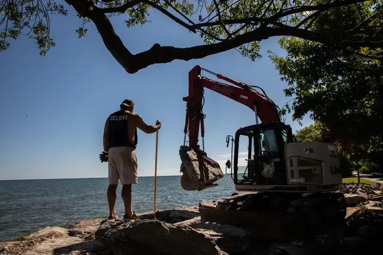 Workers reinforce a rock wall in front of a residential house on the shore of Lake Ontario in Greece, New York, on July 28, 2020. Image by Zbigniew Bzdak/Chicago Tribune. United States, 2020.