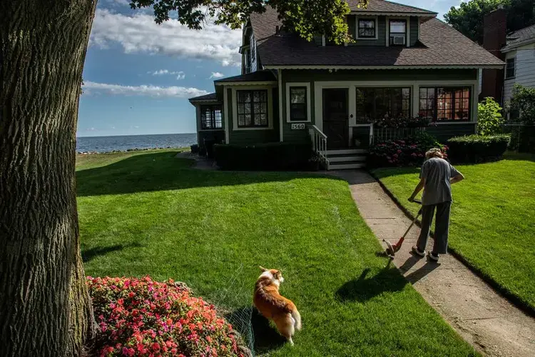 Nancy Sullivan, with dog Carter, tends to her house along the shore of Lake Ontario in Greece, New York, on July 30, 2020. She has lived at this house for the past 55 years and recently spent some of her retirement money to repair her seawall. Image by Zbigniew Bzdak/Chicago Tribune. United States, 2020.<br />
