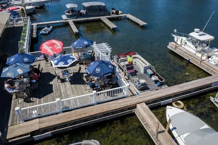People dine on a patio at Captain Jack's Good Time Tavern in Sodus Point on Lake Ontario in New York, on July 30, 2020. Shown are the new dock and pathways built on top of the existing dock below. Image by Zbigniew Bzdak/Chicago Tribune. United States, 2020.