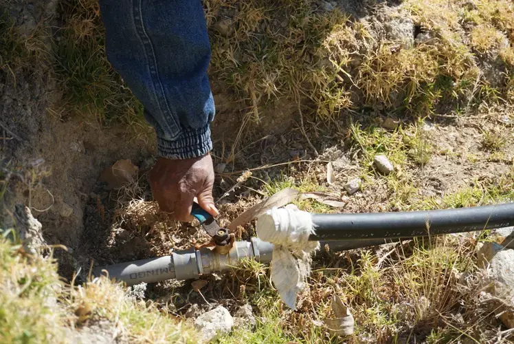 Gabino demonstrates the valve at the base of the reservoir. Image by Audrey Fromson. Peru, 2019.