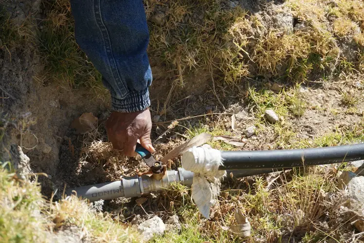 Gabino demonstrates the valve at the base of the reservoir. Image by Audrey Fromson. Peru, 2019.