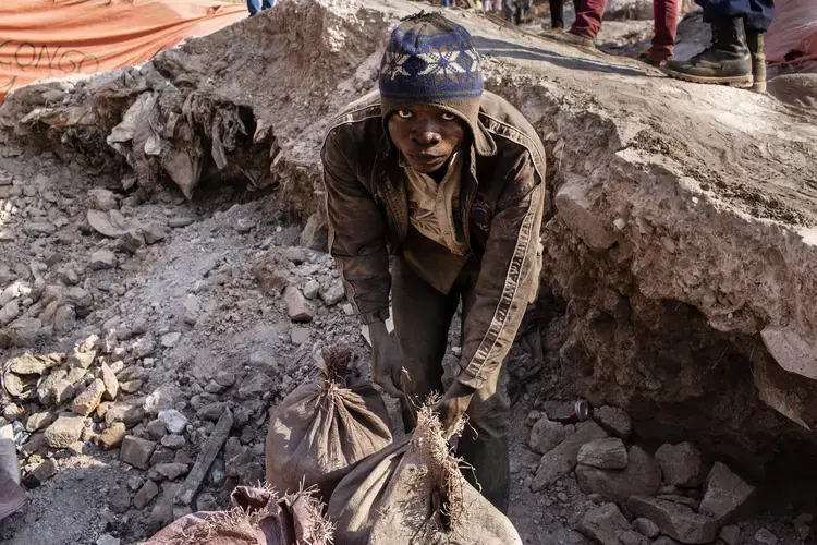 A miner ties up bags of cobalt inside the Congo DongFang mine in Kasulo. Image by Sebastian Meyer. Democratic Republic of the Congo, 2018.