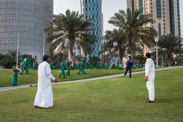 During free time, construction workers watch others play games. Image by OM. Qatar, 2017.