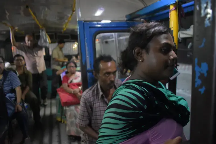 Sintu, like many transgender individuals, relies on street economies such as dancing for survival. Traveling all across Kolkata, she spends a large portion of her life on public transportation. Buses and trains across India are divided by gender with painted signs. There is only standing room on this bus, but she always sits in the 'Gentlemen's' section. Image by Siyona Ravi. India, 2017.