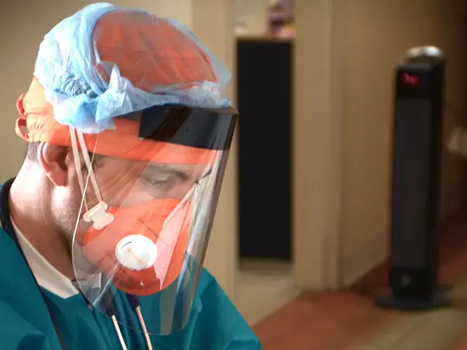 Federico Herrera, dressed in PPE, examines a Covid-19 test. Image courtesy of Esperanza Health Centers. United States, 2020.