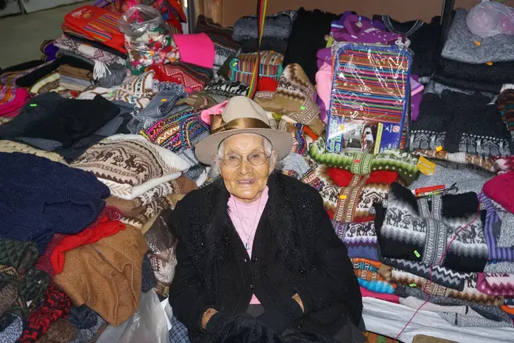 Ludmila Román Iparraguirre, a survivor of the 1941 flood, sitting in her daughter's shop at the artisan market in Huaraz. Image by Audrey Fromson. Peru, 2019.