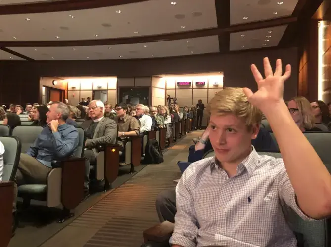 Nico Gentile, a student at Sandwich High School on the Cape, raises his hand during a question and answer session. Gentile urged lawmakers to support sustainable development and shared information about the Cape and Islands Youth Climate Action Summit he organized for Nov. 6, 2019 at the forum. Image by Indira Lakshmanan. United States, 2019.<br />
