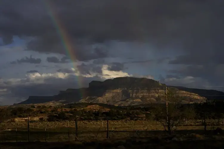 A rainbow is seen in the distance from the closed Chilchinbeto Church of the Nazarene in Chilchinbeto, Ariz., on the Navajo reservation on April 21, 2020. Image by AP Photo/Carolyn Kaster. United States, 2020.