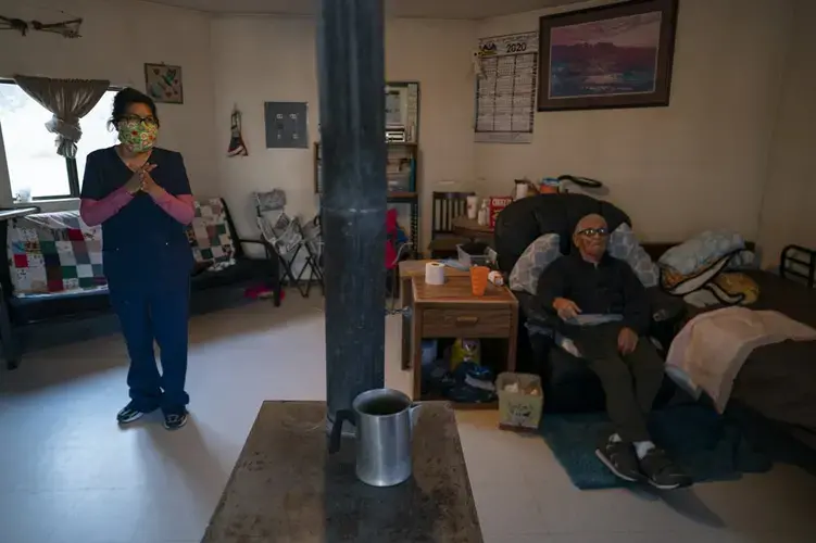 Mabel Charley, left, applies hand sanitizer as she arrives to care for her home-bound uncle in his hogan, a traditional Navajo dwelling, in Chilchinbeto, Ariz., on the Navajo reservation on April 21, 2020. The Navajo reservation has some of the highest rates of coronavirus in the country. Image by AP Photo/Carolyn Kaster. United States, 2020.