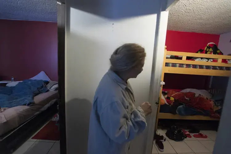 Enedis Flores checks on her sleeping children in her husband's Tijuana apartment on Nov. 29. Image by Amanda Cowan. Mexico, 2019.