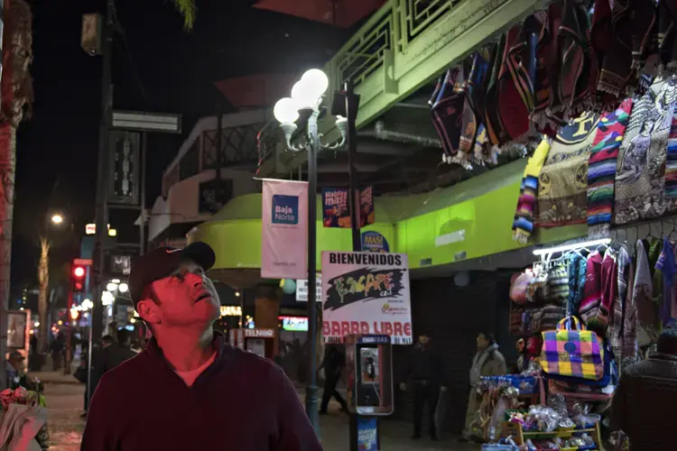 Emergency lights illuminate Ramon Flores, as crews tend to a person who collapsed in a crepe shop along Avenida Revolucion in Tijuana, Mexico, where Ramon’s family had stopped to get a treat Nov. 30. Image by Amanda Cowan. Mexico, 2019.