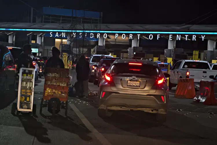 Street vendors greet motorists as they prepare to cross the border into the United States from Mexico at the San Ysidro Port of Entry on Dec. 1. Image by Amanda Cowan. Mexico, 2019.