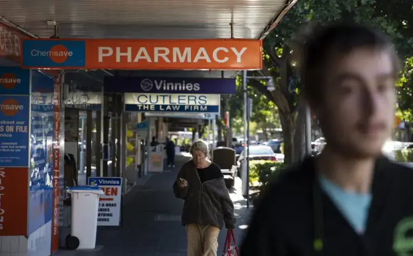 Sam Ware, 22, right, walks by the pharmacy where he used to get some of his opioid prescriptions filled in The Entrance, Central Coast, Australia, Thursday, July 25, 2019. Image courtesy of David Goldman. Australia, 2019.