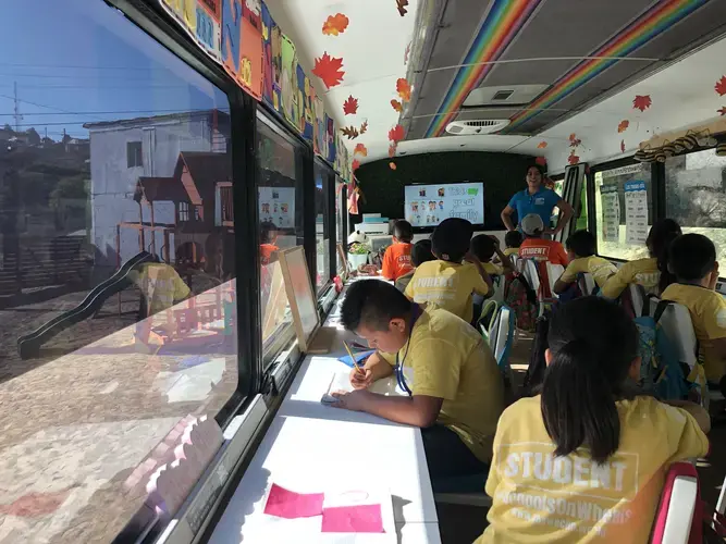 Lessons are taught on a bus that’s been turned into a classroom. Students learn in English and in Spanish. Here, teacher Sandra Rodríguez explains words related to family, such as mother (“madre”) and father (“padre”). Image by Jaime Joyce. Mexico, 2019.