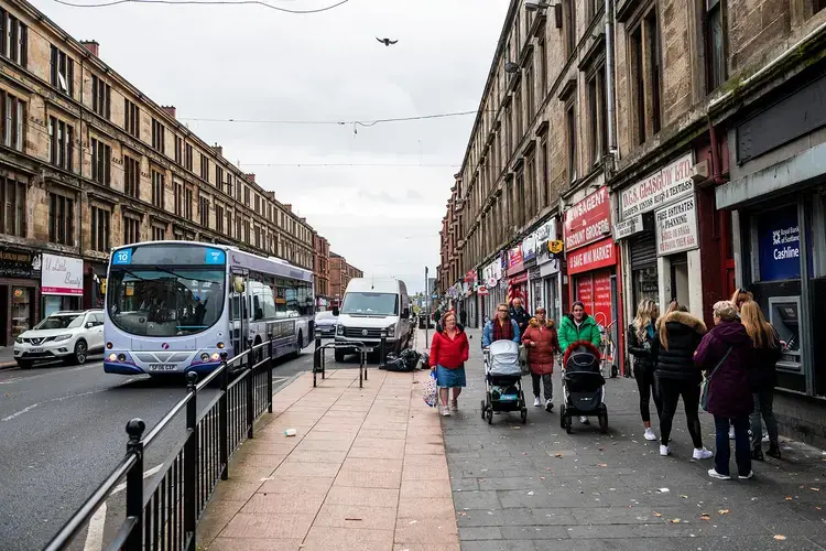 People walk and wait in line to use an ATM on Saracen Street in Possilpark, Glasgow, Scotland. Image by Michael Santiago. United Kingdom, 2019.