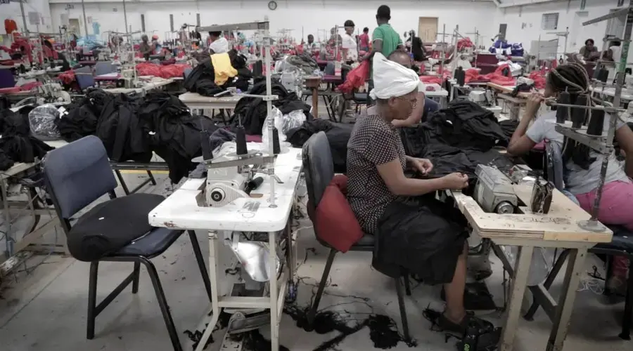 A female Haitian factory worker sews at Cleveland Manufacturing in Port-au-Prince, Haiti. The factory is among several working with two nonprofits to screen female workers for cervical cancer. Image by José A. Iglesias. Haiti, 2018.