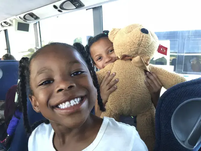 BACK ON THE ROAD After a six-hour visit, it’s time to go home. Get on the Bus gave each child a teddy bear. Mayal had a plan for hers. “I want to go to sleep,” she said. “This is going to be my pillow.” Image by Jaime Joyce. United States, 2018.