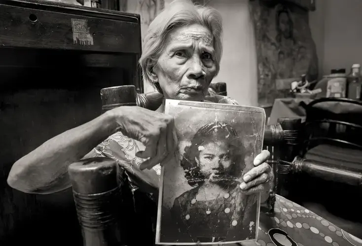Fedencia Nacar David holds her photo for an application to work as a maid. She was 15. A year before, a Japanese soldier sliced her ear and threatened to behead her if she didn't go to a garrison with him; she was raped over 10 days. 'It still hurts,' she says. 'I was innocent. Why did that happen to me?' She kept her past from her children until 'comfort women' began speaking out in the 1990s. Image by Cheryl Diaz Meyer. Philippines, 2019.