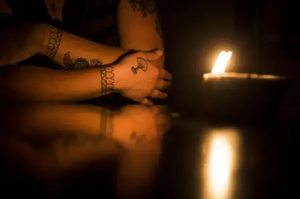 Saunders shows a tattoo of an ulu, Inuit cutting tool, on her right hand with traditional Inuit tattoos on both wrists illuminated by a whale oil lamp at her apartment in the military base town of Happy Valley-Goose Bay, Labrador. Image by Michael G. Seamans. Canada, 2019.