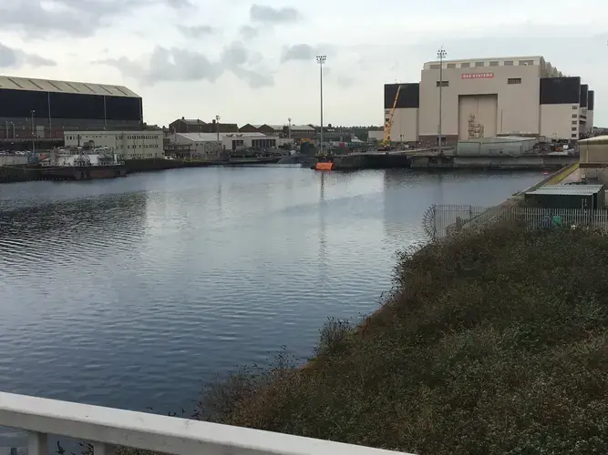 View from the bridge. The BAE Systems Trident submarine shipyard. A nuclear submarine is viewable half submerged in the water. Image by Matt Kennard. United Kingdom, 2017.