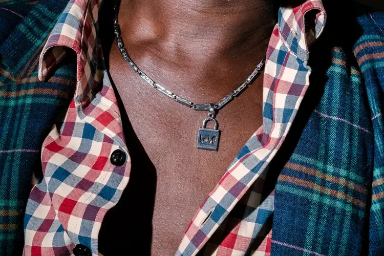 Sweet Love, a transgender woman and the chairperson of Children of the Sun, poses for a portrait with a necklace from her boyfriend. She sits at the Children of the Sun safe house, which shelters at-risk and in-need LGBTQ+ persons. Image by Jake Naughton. Uganda, 2017.