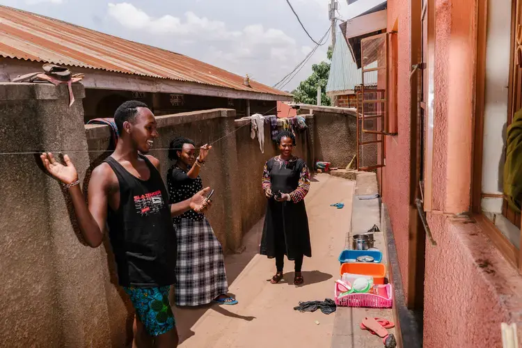 Javan outside the family's home, with her mother and cousin. Image by Jake Naughton. Uganda, 2017.