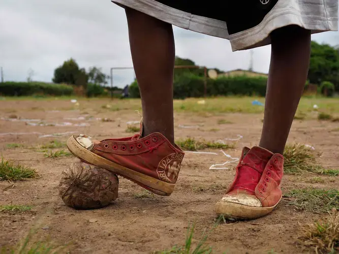 Children are especially at risk from lead poisoning and they ingest dust while playing, on football fields and elsewhere in Chowa township, next to the former mine site. Image by Larry C. Price. Zambia, 2017.