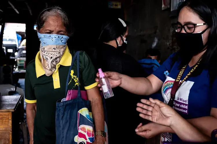 Rosalie Natividad shares her alcohol spray with an old lady at the market. Image by Xyza Cruz Bacani. Philippines, 2020.