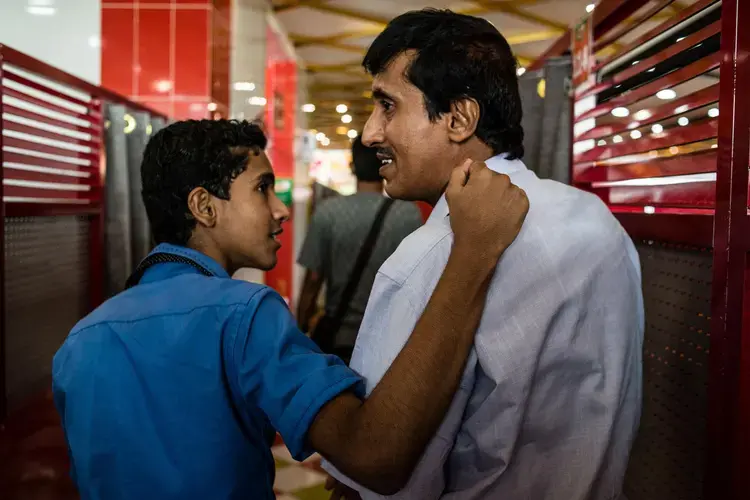 Fathi al Atef (right) and his son, Hamza (left), leave a restaurant in Aden after having lunch together. Image by Alex Potter. Yemen, 2018.