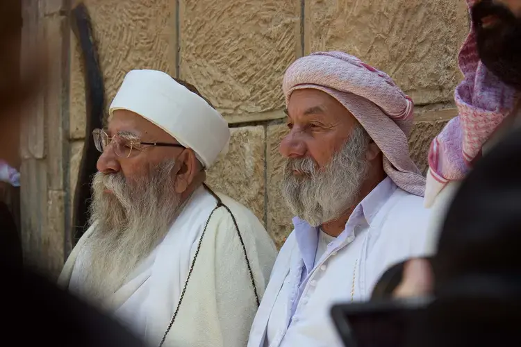 Yazidi religious leaders address a group of about 80 women and children on the eve of their departure to Germany in May 2015. Image by Emily Feldman. Iraq, 2015.
