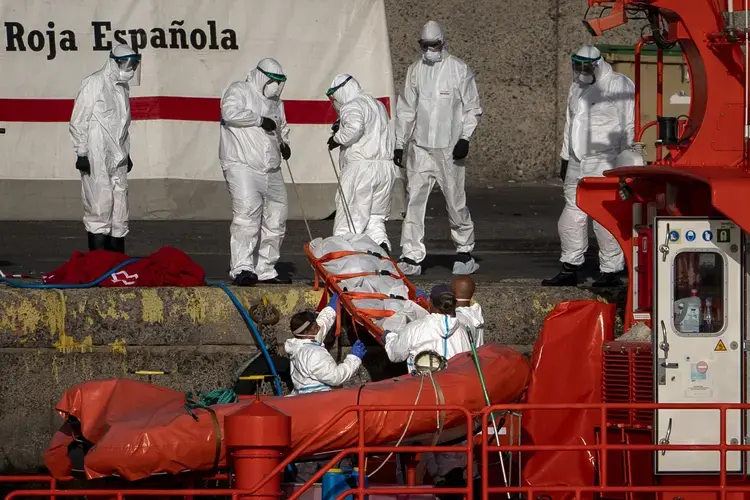 Emergency workers carry a migrant’s body after being found dead by the Spanish Maritime Rescue Service, at the Arguineguin port in Gran Canaria island, Spain, on Friday, Aug. 21, 2020. Image by Emilio Morenatti/AP Photo. Spain, 2020..jpeg