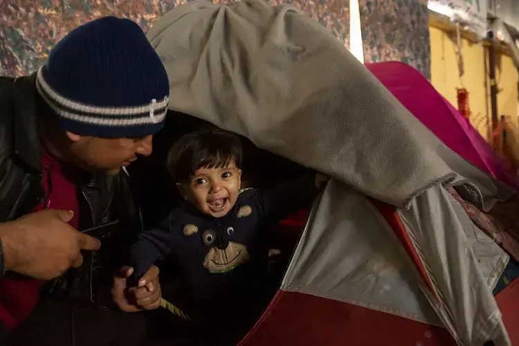 Juan Carlos plays with his youngest child in a shelter in Tijuana. He owned a small bakery in El Salvador but fled with his family last autumn after gang members demanded money and threatened their lives when he couldn’t pay. Image by Erika Schultz. Mexico, 2019.