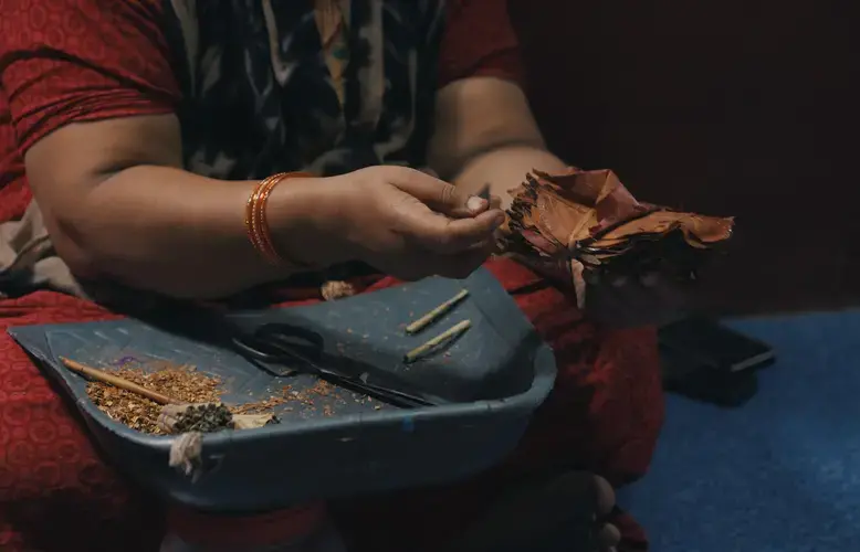 A beedi worker in Karnataka explaining why fingerprints fade during the process of handling tobacco while rolling beedis. Image by Pallavi Puri. India, 2019.