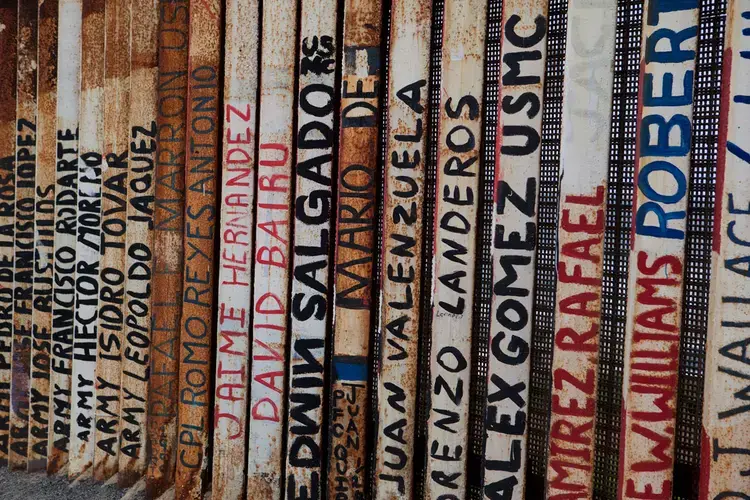 A section of the U.S-Mexico border wall is painted with art and the names of deported U.S. veterans in Tijuana. Image by Erin Siegal. Mexico, 2019.