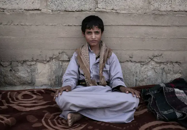 Abdel-Hamid, a 14-year-old former child soldier, poses for a photograph at a camp for displaced persons where he took shelter, in Marib, Yemen, in this July 27, 2018, photo. Tasked by Houthi rebels to carry supplies to other fighters in the high mountains, he says he saw children get shot for not obeying orders. He said the front-lines are full of children. Image by Nariman El-Mofty / AP News. Yemen, 2018.