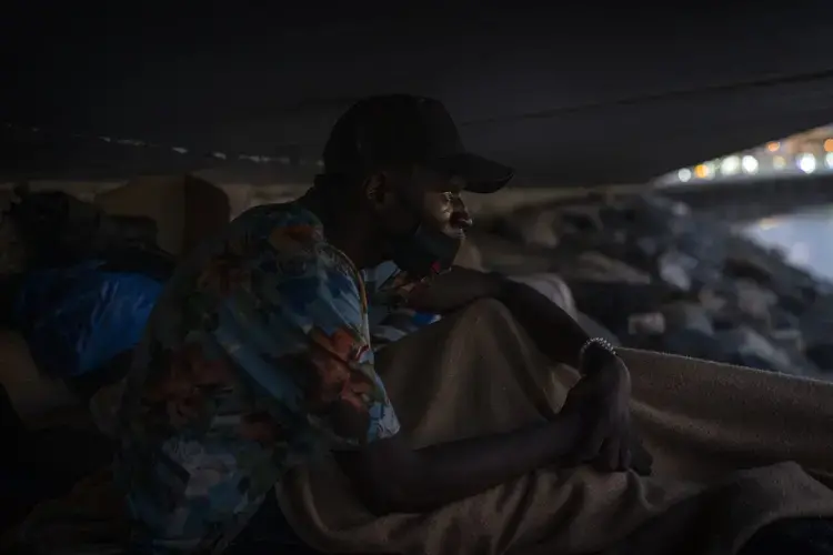 Khalid, a migrant from Gambia, sits on a breakwater under a bridge in Gran Canaria island, Spain, on Saturday, Aug. 22, 2020. Image by Emilio Morenatti/AP Photo. Spain, 2020.