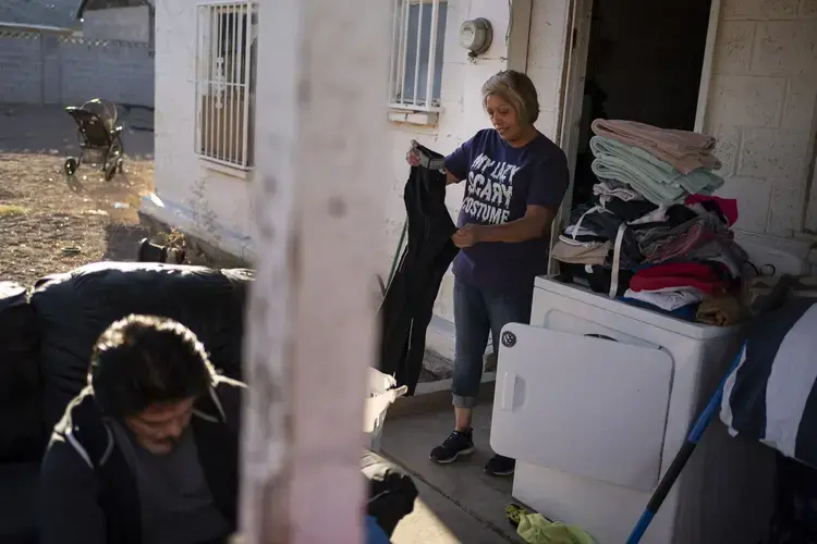 Norma Flores, 54, folds the laundry while her son works on his bicycle at their home in Henderson, Nev., Tuesday, Nov. 10, 2020. Image by Wong Maye-E / AP Photo. United States, 2020.