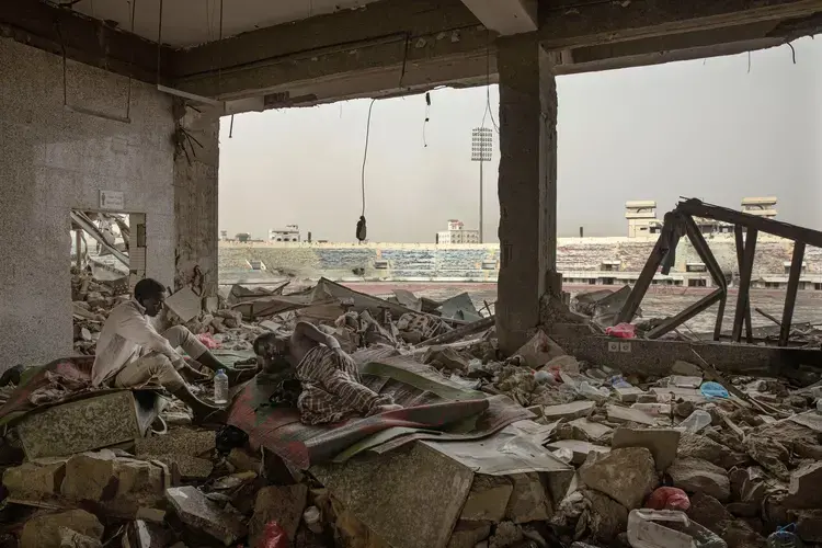 Ethiopian migrants take shelter in the '22nd May Soccer Stadium,' destroyed by war, in Aden, Yemen. Image by AP Photo/Nariman El-Mofty. Yemen, 2020.