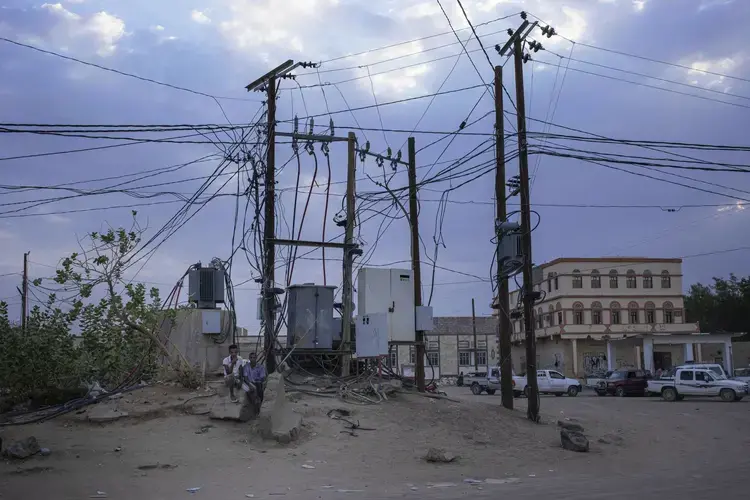 Ethiopian Oromo migrants sit under electric cables in Al Hosoun area, where they gather to find work, in Marib, Yemen. Image by AP Photo/Nariman El-Mofty. Yemen, 2020.