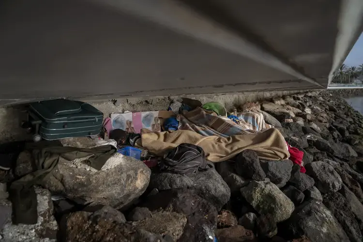 Khalid, a migrant from Gambia, sleeps on a breakwater under a bridge in Gran Canaria island, Spain, on Saturday, Aug. 22, 2020. Image by Emilio Morenatti/AP Photo. Spain, 2020.