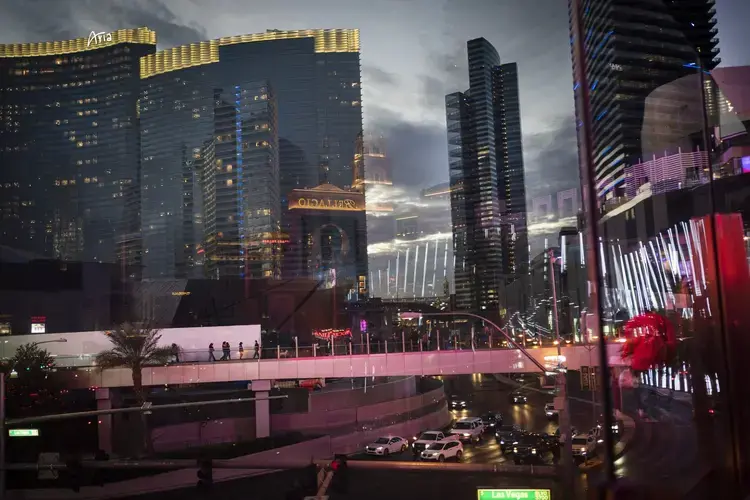 Casinos and other businesses are seen reflected in the glass walls of an overpass along the Las Vegas Strip. The coronavirus hit the Las Vegas economy particularly hard. Visitors to the area plummeted by more than 90 percent in a little over a month. The state's unemployment rocketed to 28 percent, the worst in the nation and a level not seen even during the Great Depression. Image by Wong Maye-E / AP Photo. United States, 2020.