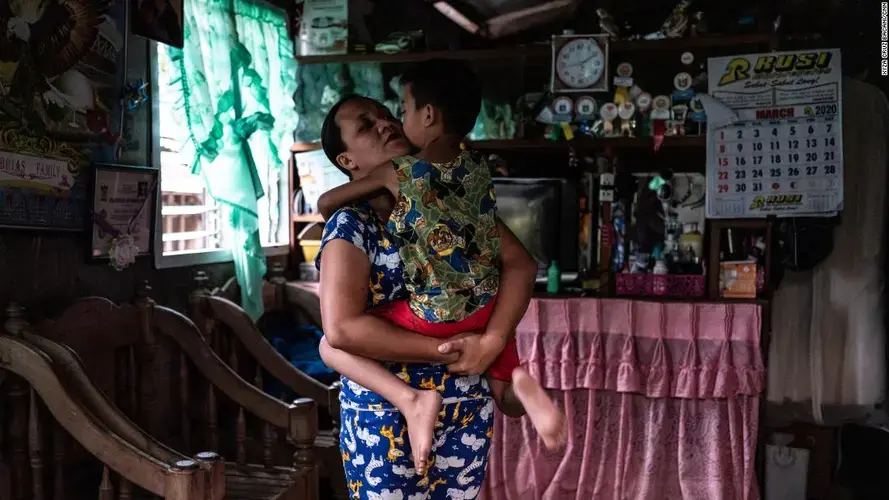April Abrias hugs her son, Yohan, inside their home after she has disinfected and changed her clothes. Image by Xyza Cruz Bacani. Philippines, 2020.
