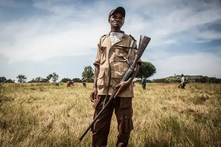 Yahaya Musa, 37, stands guard as farmers harvest grain in Barkin Ladi in October. Musa was present during a deadly attack on farmers in June by men thought to be cattle herders. Image by Jane Hahn. Nigeria, 2018.