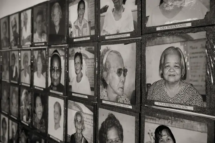 Images of the estimated 1,000 Philippine 'comfort women' who were enslaved and sexually victimized by the Japanese Imperial Army during World War II fill a wall at the offices of Lila Pilipina. The organization of World War II victims of sexual war crimes has helped the 'comfort women' in their fight for compensation. Image by Cheryl Diaz Meyer. Philippines, 2019.