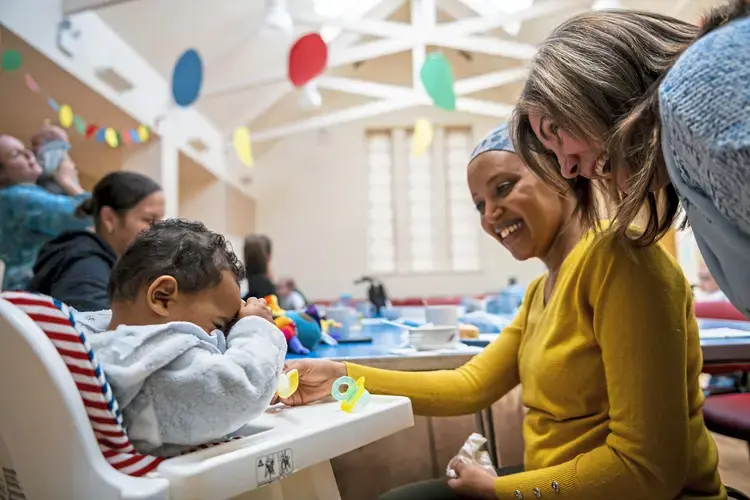 Seven-month-old Eliad Abrha hides his face as he plays with his mother Hanna Abrha, center, and Mary Stewart, NHS health specialist, at Cafe Stork, Tuesday, Oct. 21, 2019, at Parkhead Congregational Church in Glasgow. Image by Michael M. Santiago. United Kingdom, 2019.