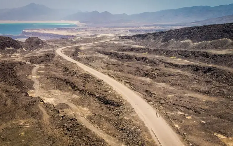 Ethiopian migrants walk along Djibouti’s coastal road north to Obock, past Lake Assal, one of the lowest and hottest places on earth. Image by Charlie Rosser. Djibouti, 2018.